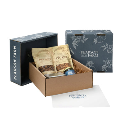 Gift box with bags of pecans, tin of chocolate, and jar of preserves. Blue lids with the name Pearson Farm standing beside box